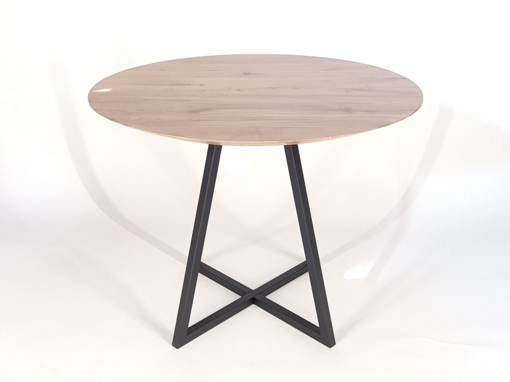 Cross dining table base in black under a round wood top